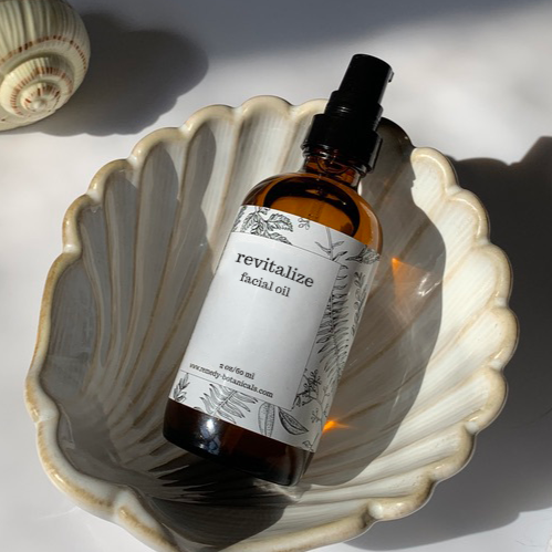 Top view of a bottle of Revitalize facial oil resting in a decorative pearl shell figurine,