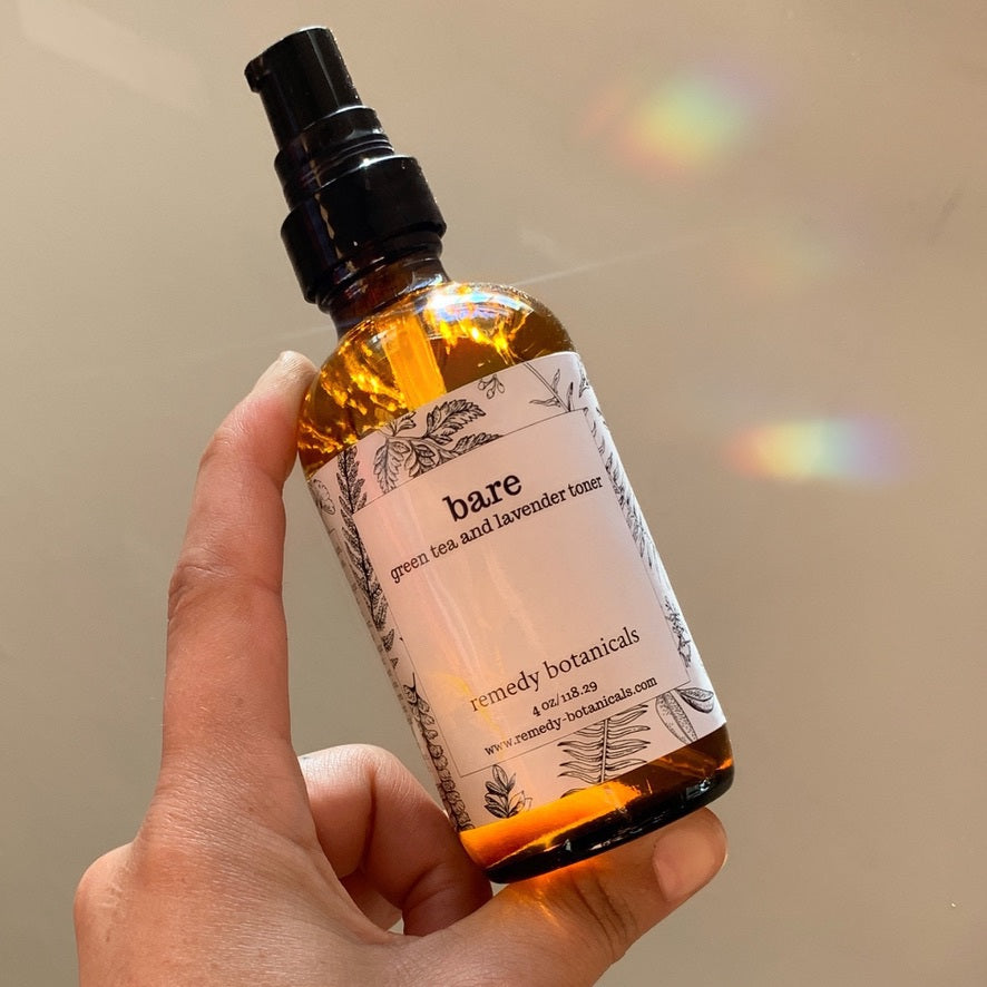 A 4oz bare bottle is held up against the light, with sun rays streaming through the bottle