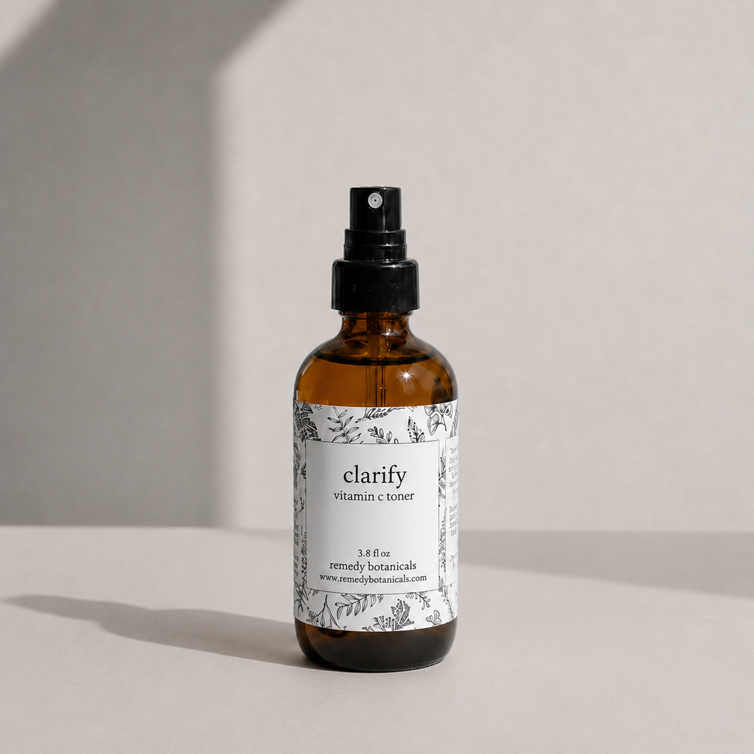 An amber glass spray bottle of clarify on a soft beige background with natural light.