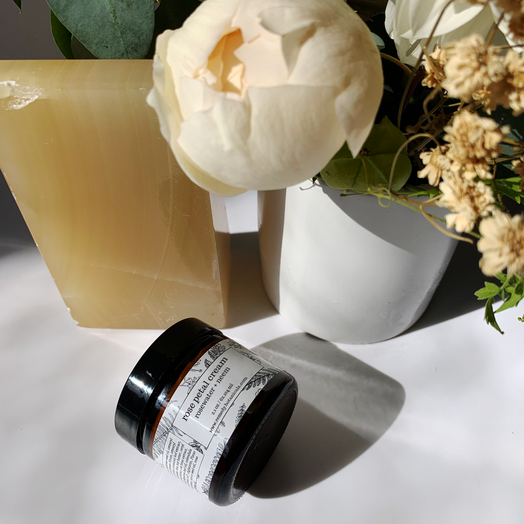 Top view of a bottle of Rose Cream beside bright orange bars, with variant of vibrant florals.