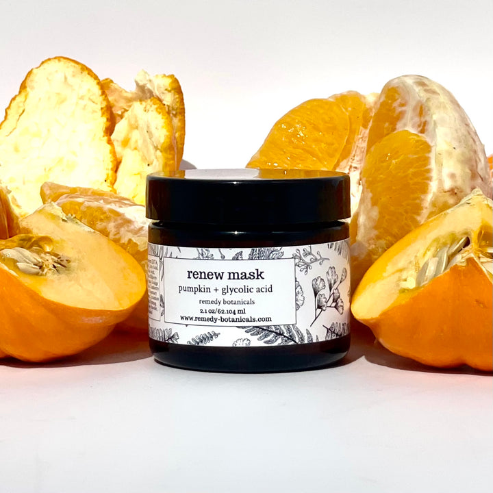 Front-facing amber jar nestled between whole and sliced oranges, emphasizing citrus freshness.